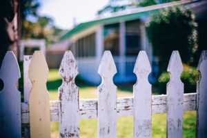 A white picket fence with a house in the background